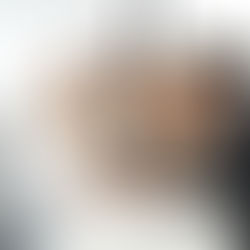 Four people focus on documents and a laptop in a bright meeting room. Charts are visible on paper. The mood is collaborative and serious.