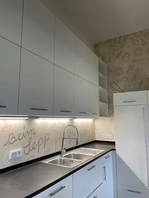 Carta da parati impermeabile personalizzata per una nuova cucina con una frase personale e piccole illustrazioni di cibi.