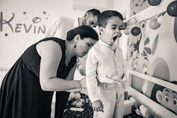 menino boceja enquanto padrinhos ajudam a vestir