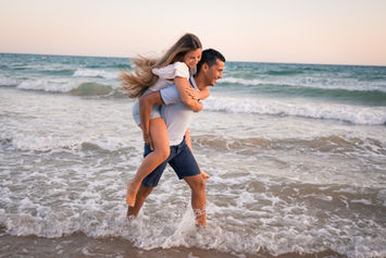 Ela às cavalitas dele a rir na praia