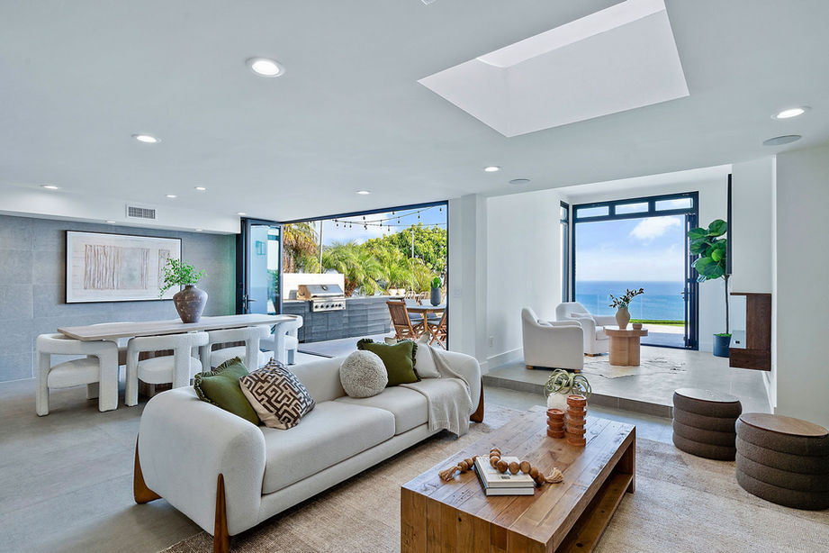 Exterior shot of a luxury villa featuring large glass sliding doors, a swimming pool, and outdoor lounge furniture.