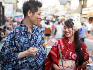 Japanese man and woman in colorful kimonos smiling at each other at a summer festival in Japan