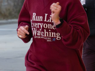 Torso of woman wearing red sweater and running.