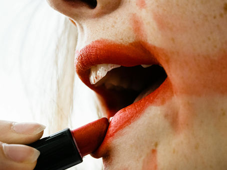 lips with messy red lipstick being applied