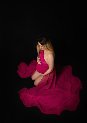 Frau auf Knie, sie schaut sein Babybauch, schwarze Hintergrund, Bordeaux Kleid