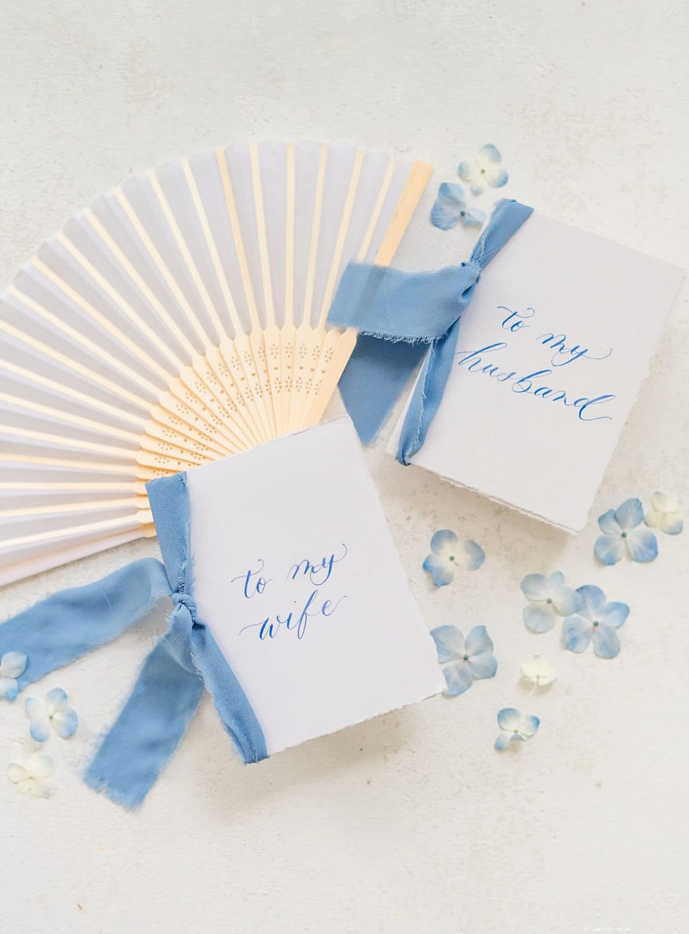 Flat Lay photo of Handmade Vow Booklets with Raw Paper Edges and Light Blue Chiffon Ribbon
