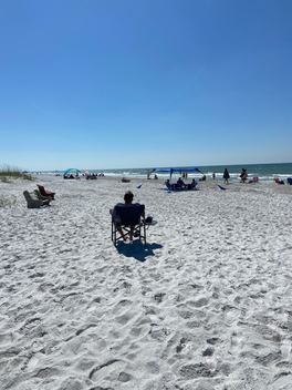 Indian Indian Shores Beach. Person sitting on chair facing the water.