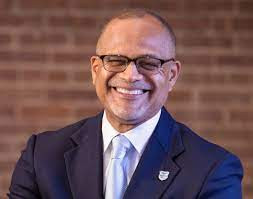 NYC School Chancellor Banks wearing a navy suit and glasses.