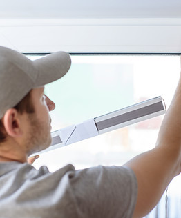 Man installing gray pleated blinds on the window.jpg