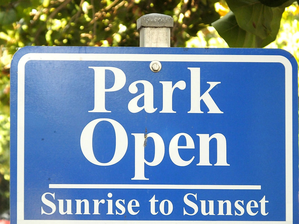 Blue sign with white text that reads "Park Open Sunrise to Sunset"