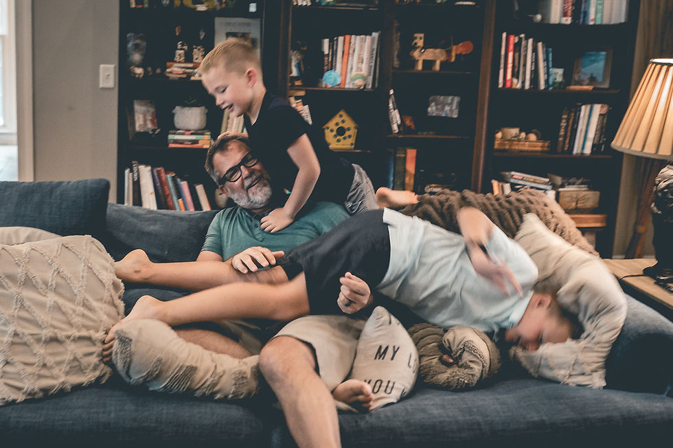 dad and two sons wrestling on couch