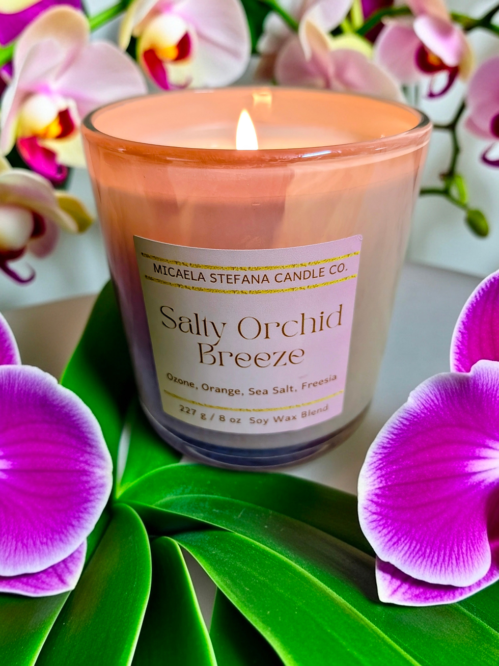 Salty Orchid Breeze soy wax candle in a blush irridescent jar with candle lit.