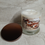 Thumbnail: Spiced Honey & Tonka Candle with a bronze metal lid beside the candle.