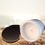 Thumbnail: Seaside Bliss candle on it's side against a beach back round with rose gold lid off to display candle..