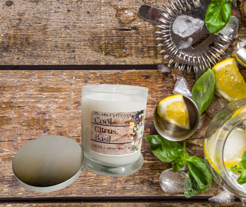 A Cool Citrus Basil candle next to fresh lemon, basil leaves, and ice on a wooden background.