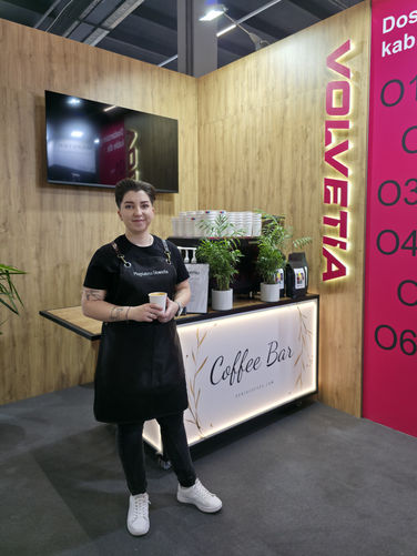 Profesjonalna baristka Serio.coffee spot stojąca przed mobilnym barem kawowym na stoisku klienta podczas targów w Krakowie