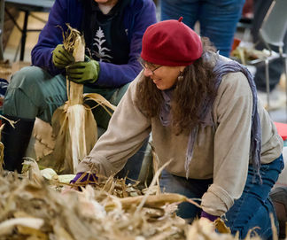A woman fills a bushel basket with corn