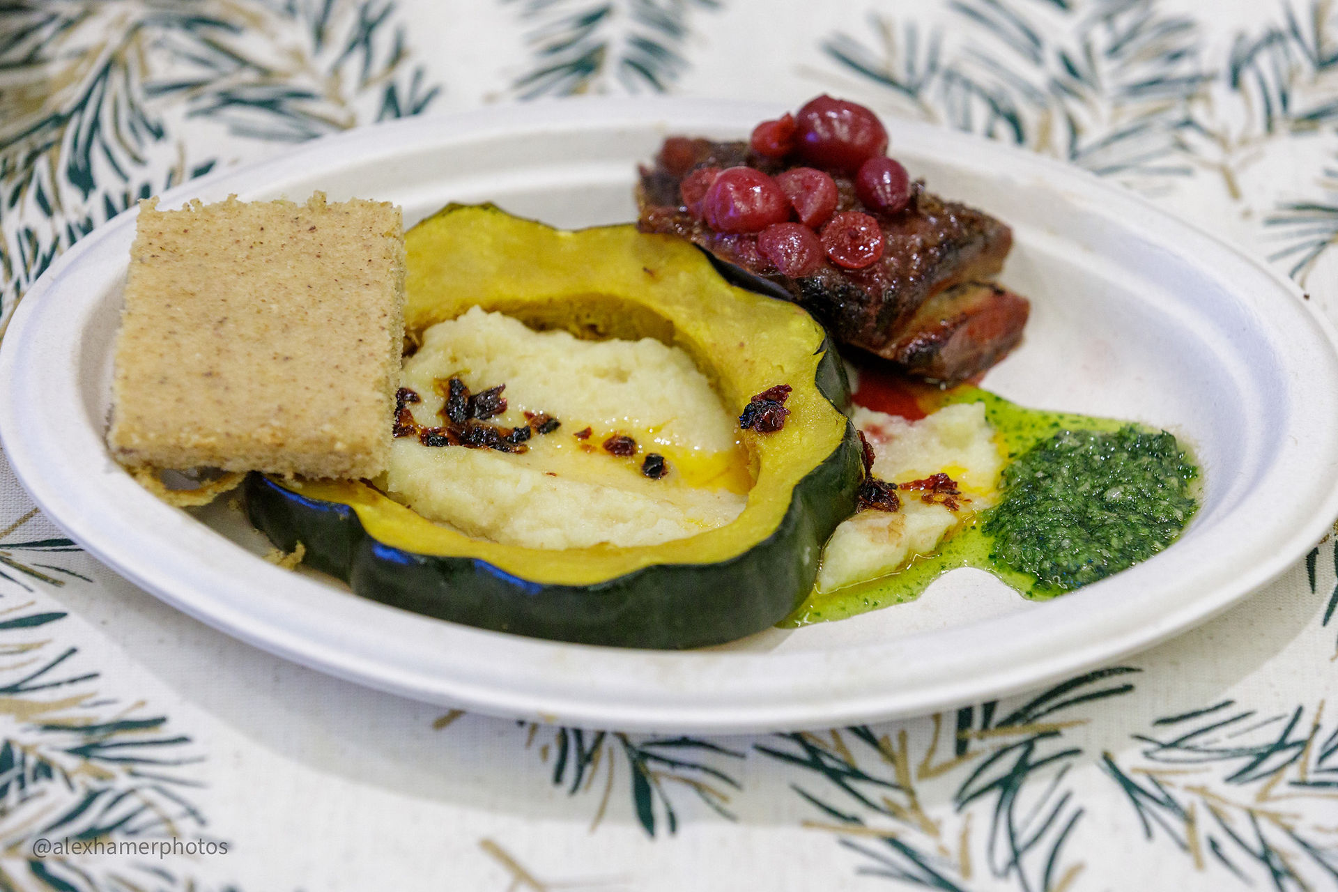An aestheticly plated serving of food with corn bread, squash, and cranberries