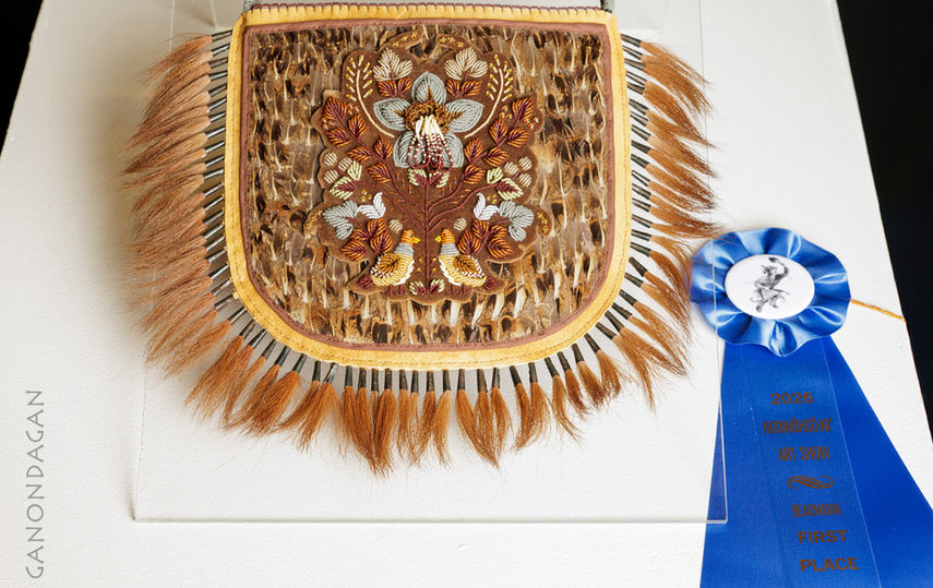 beaded and tufted purse with blue ribbon next to it