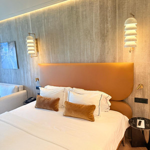 Bedroom with bed, pillows, lamps, and artwork; modern hotel suite.