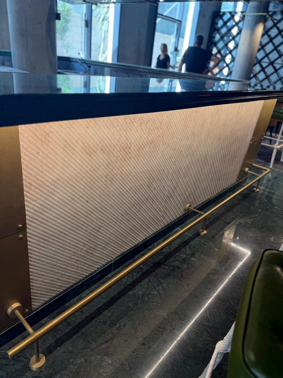 Modern bar counter with gold details and geometric wall design background.