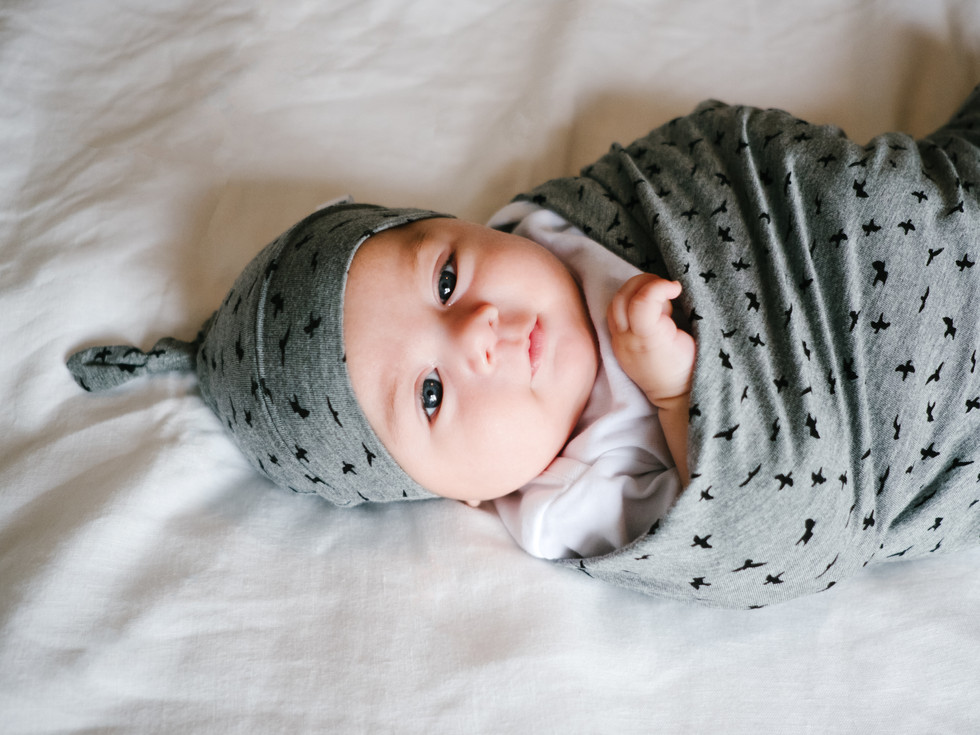 Ottawa newborn photographer - Lifestyle newborn photographer Ottawa - Mother holding baby girl in Mini Tipi bamboo blanket and top knot hat during Ottawa Gatineau branding lifestyle photography session with photographer Melanie Mathieu.