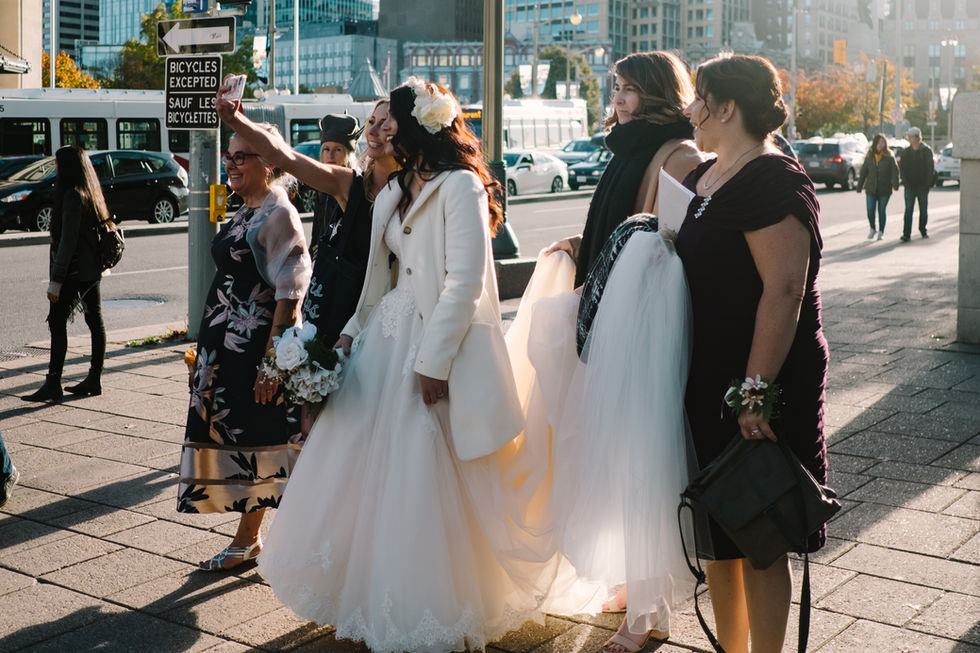 Candid photo of bride and her bridal party taking a selfie downtown Ottawa before wedding ceremony at the Metropolitain Brasserie. 