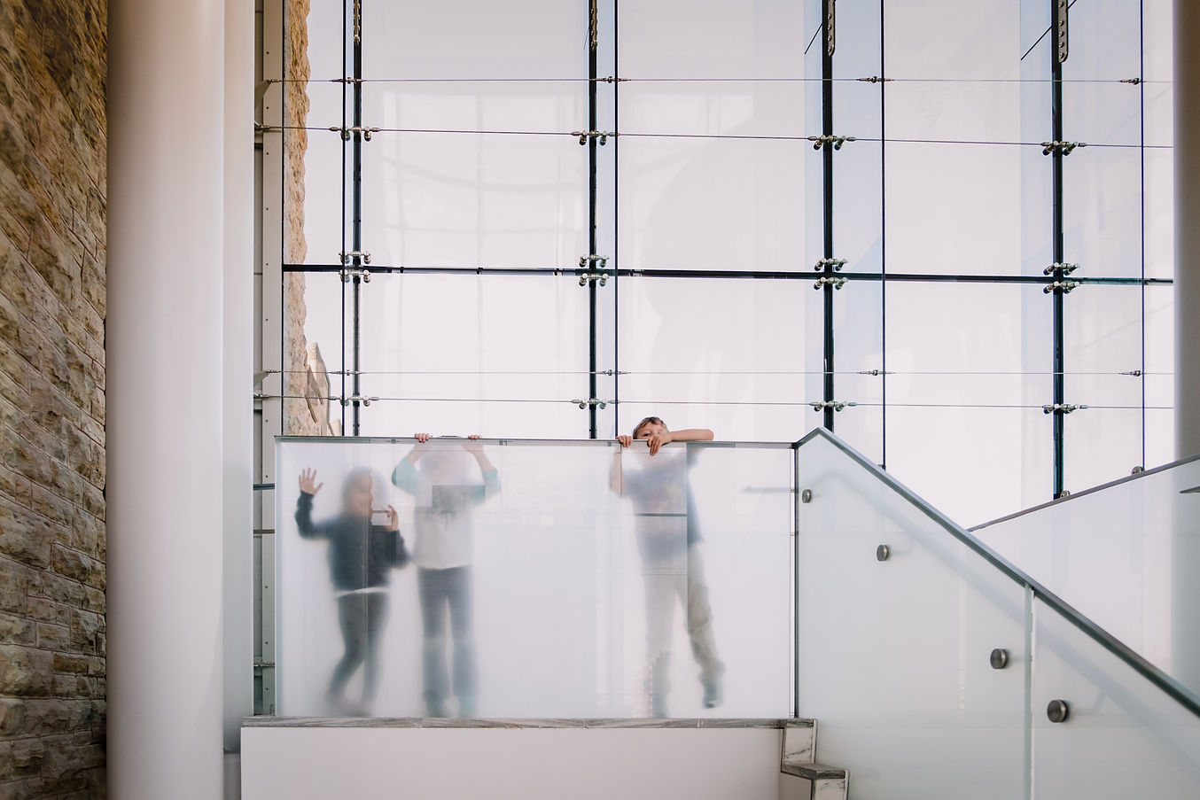 Three kids hiding behind a glass partition at the Museum of Nature in Ottawa