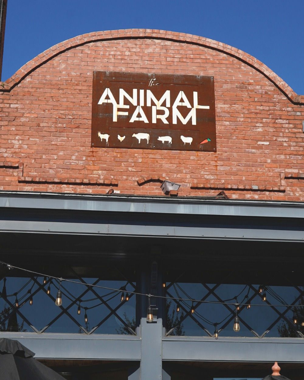 the animal farm sign on a red brick facade under a blue sky