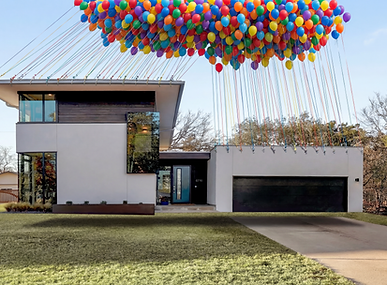Modern luxury home with a large cluster of balloons attached above the roof, creating a dramatic real estate marketing