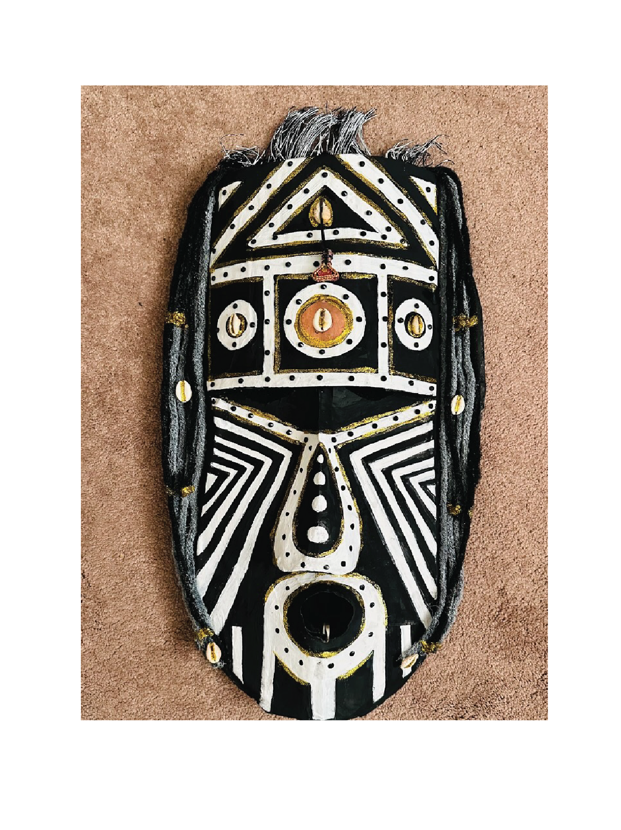 Black, white, and gold tribal mask with geometric patterns