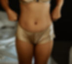 Waist down view of a woman with tan skin pulling up a pair of silk underpants.