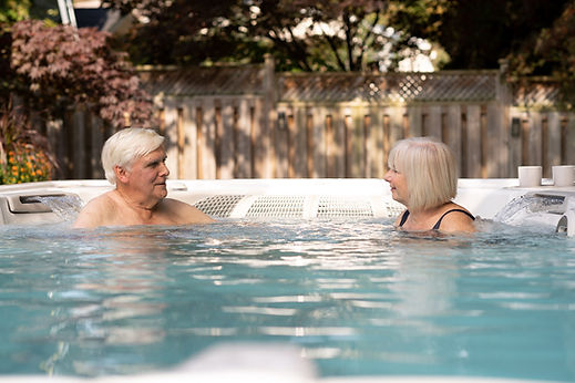 Two grandparents, a woman and man, have a relaxed chat in a family swim spa.