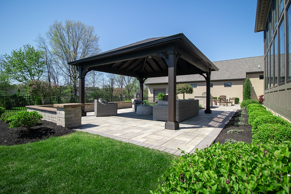 Dark wood pavilion on a stone patio with outdoor seating.