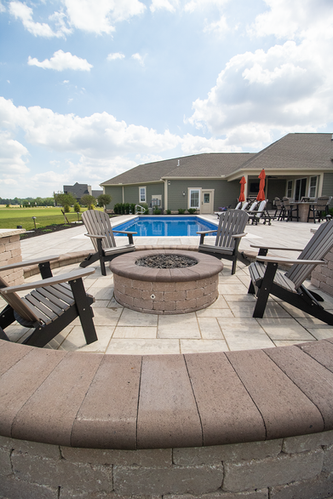 Stone fire pit with seating near a swimming pool in Sunbury, OH.