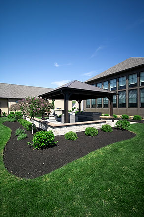 Outdoor pavilion with seating and landscaped lawn.