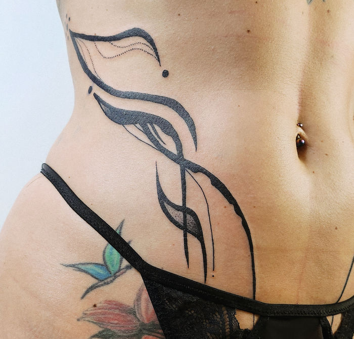 Body Flow Tattoo am Bauch in organischen Linien.