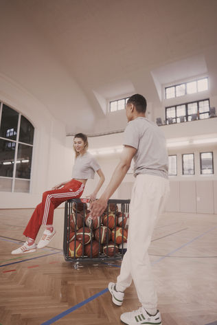 Model in adidas Forum sneakers on an indoor basketball court during Spring 2021 campaign shoot.