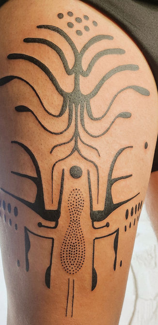 Abstraktes Symbol-Tattoo am Oberschenkel mit symmetrischem Linienmuster und Punktstruktur.