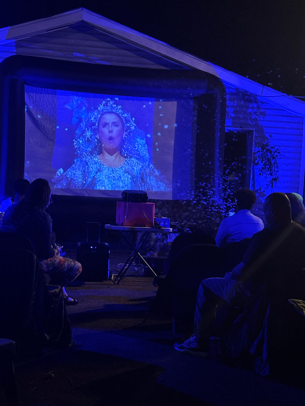 Outdoor movie screen showing The Wiz during a community movie night experience.