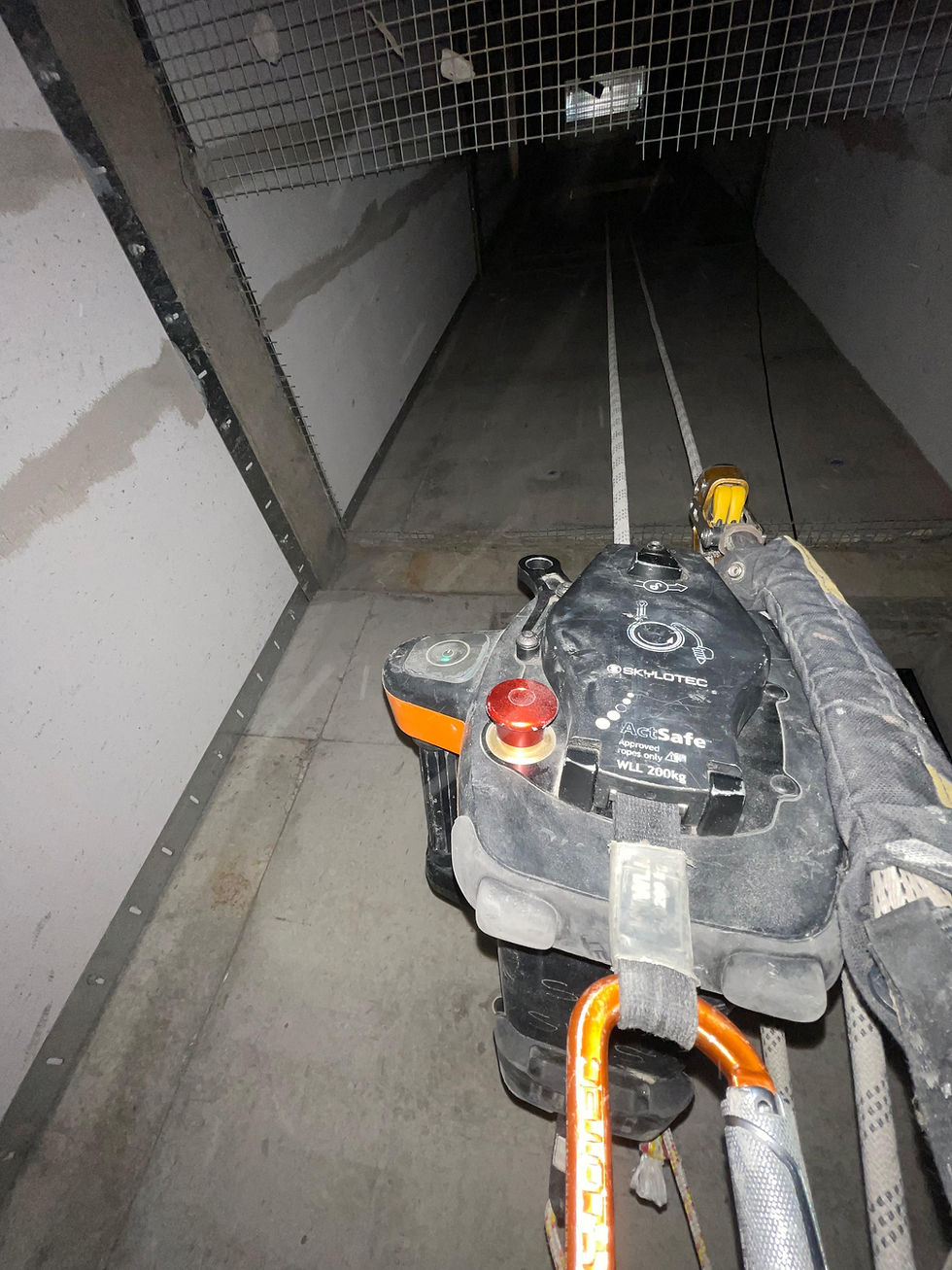 safety lines: Rope access device with orange carabiner and Skylotec ActSafe WLL 200kg sits at the top of a dark industrial shaft.