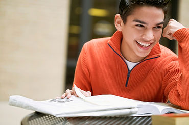 Teenage boy laughing while studying