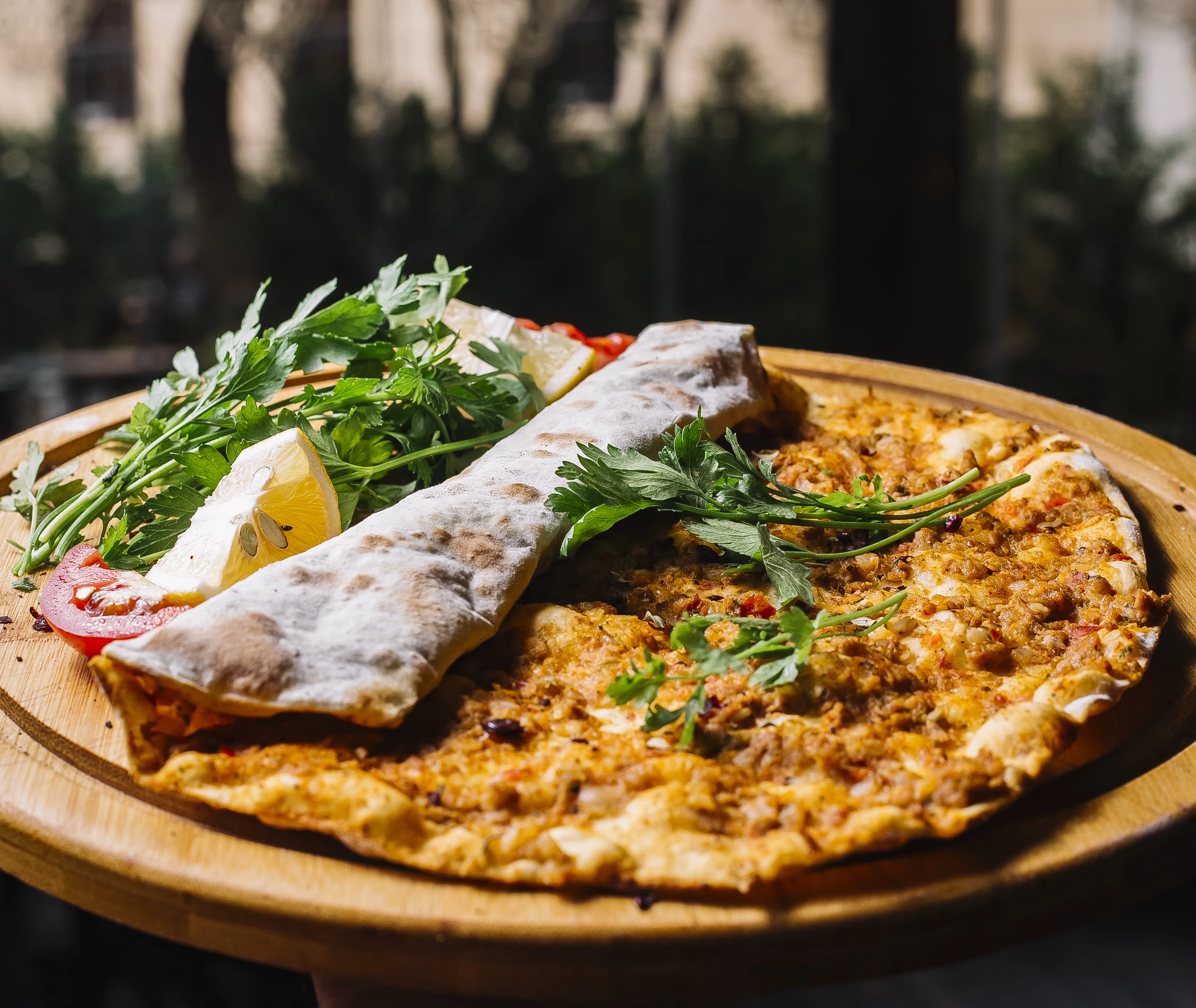 side-view-lahmajun-with-ground-meat-greens-lemons-tray.webp