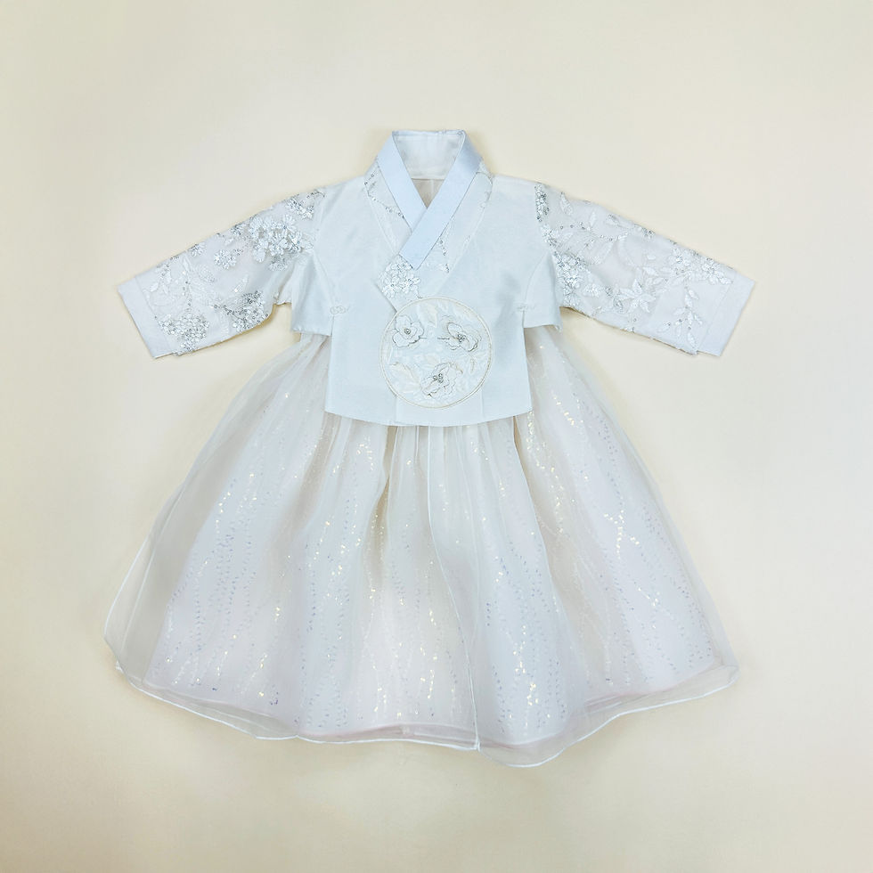 Baby girl hanbok with white floral lace jeogori, shimmering ivory skirt, and embroidered circular chest patch