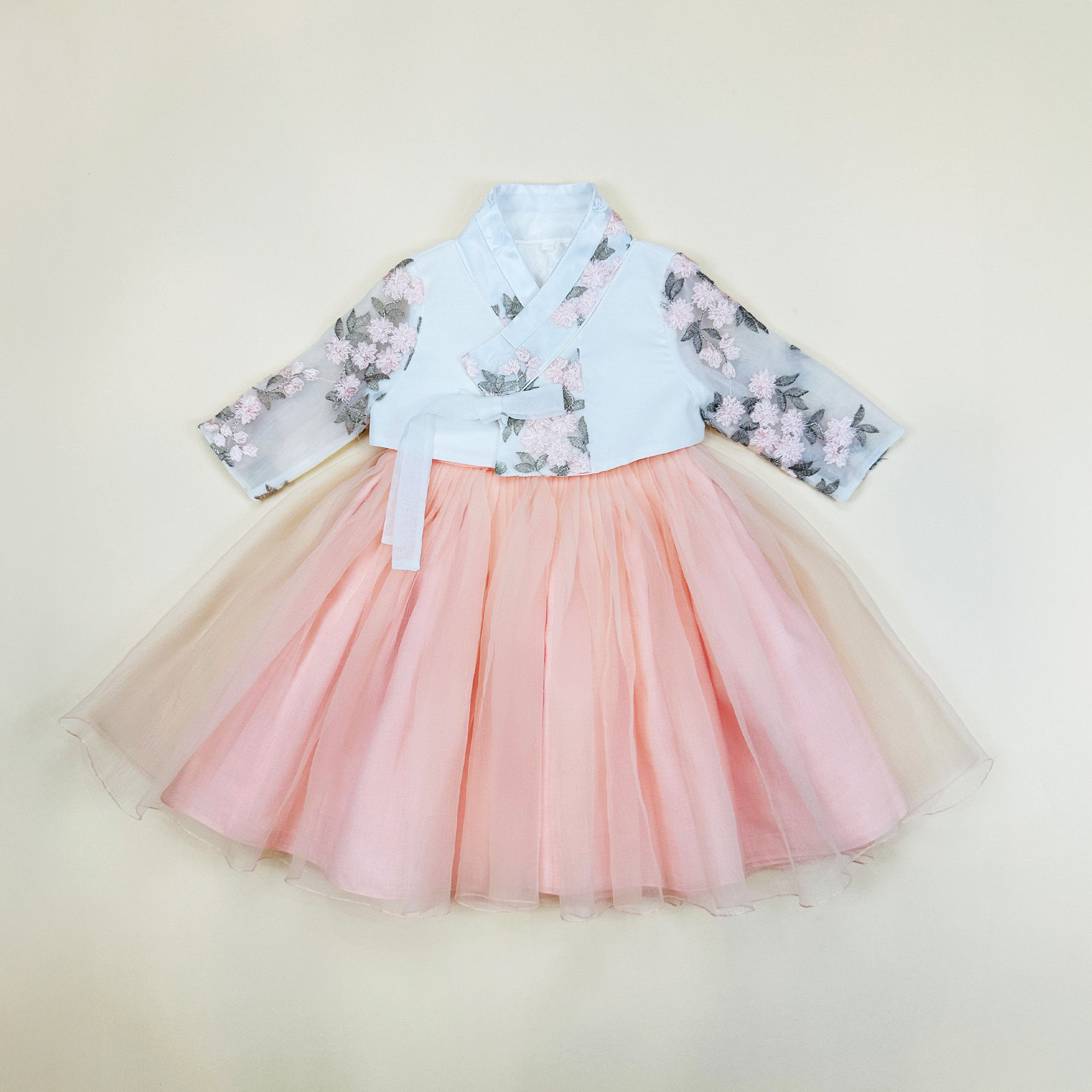 Baby girl hanbok with white jeogori featuring sheer floral embroidered sleeves and a soft peach tulle skirt