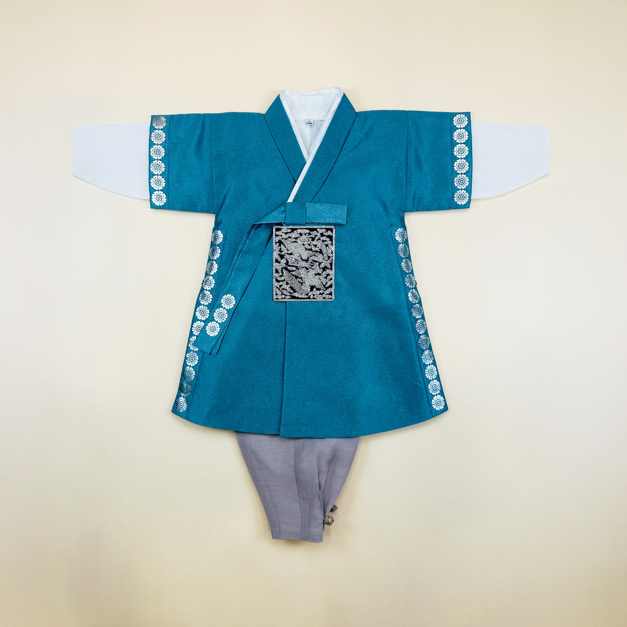 Baby boy dohl hanbok with teal robe featuring silver circular embroidery on sleeves and sides, paired with white pants and a