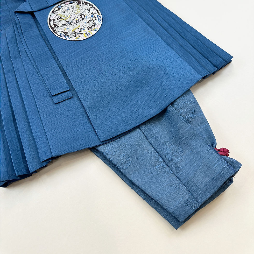 Thumbnail: Baby boy dohl hanbok featuring a pleated deep blue top with embroidered circular crest, light gray jeogori sleeves, and charc