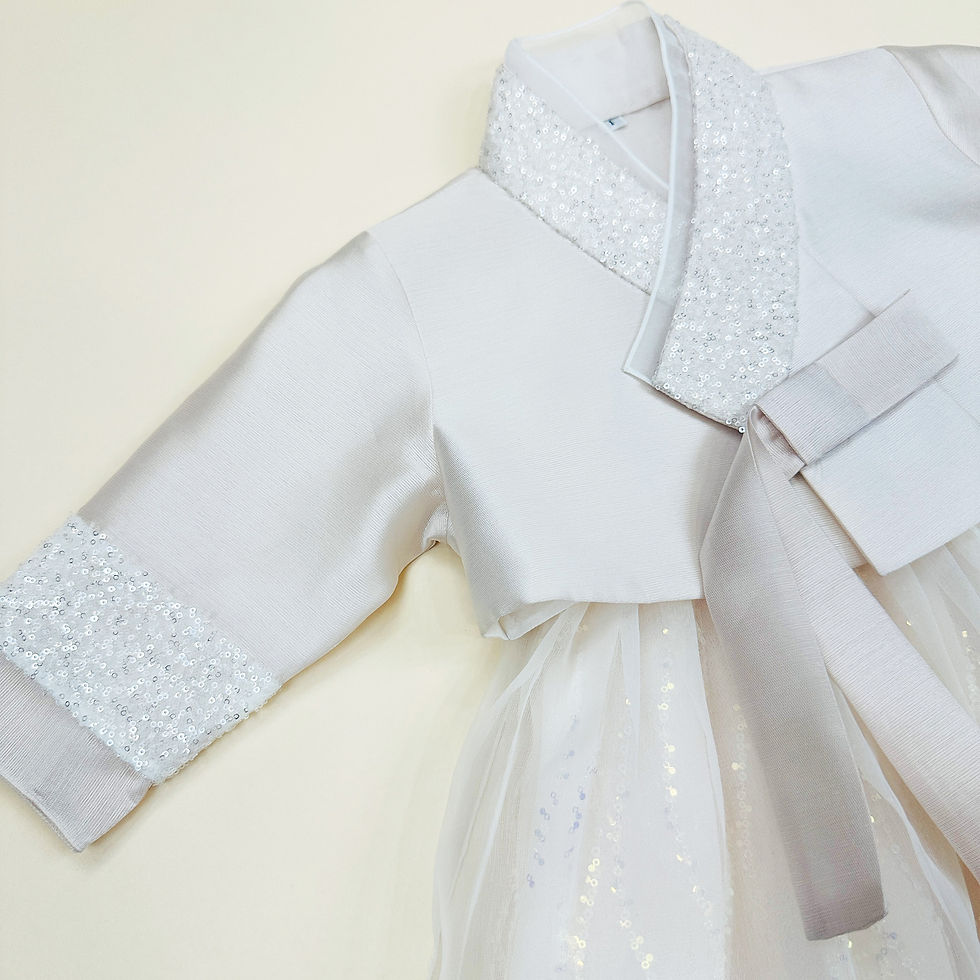 Thumbnail: Baby girl hanbok with light ivory jeogori featuring silver glitter trim and a sparkly ivory tulle skirt for first birthday ce
