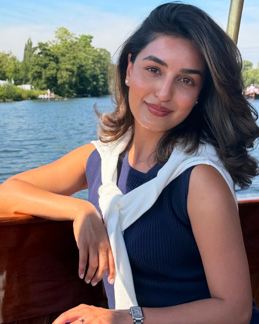 Sonam on a river boat in a navy knit top with a white jumper over her shoulders