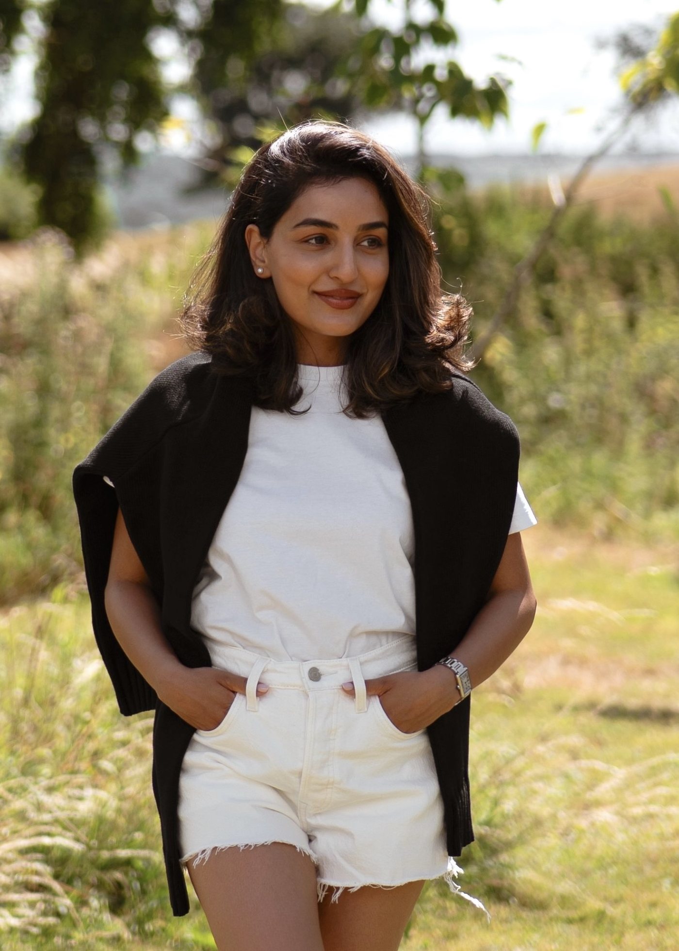 Sonam outdoors in summer in a white tee with a black jumper over her shoulders